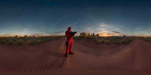 a man in all red jumpsuit standing. with his face all covered. and holding a machine gun.