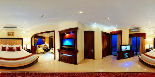 An opulent, flawlessly detailed grand matrimonial bedroom, highlighted in soft ambient light, featuring a sleek wall-mounted television, a window on the left, and an elegant door on the right, radiating an aura of luxury and meticulous perfection.