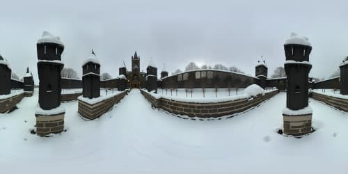 Facing the Renaissance Gothic castles straight. the castle's walls are GREY.Zooming in. in dark dim weather. snow falls on the bricks. and it looks like the castles has been attacked.